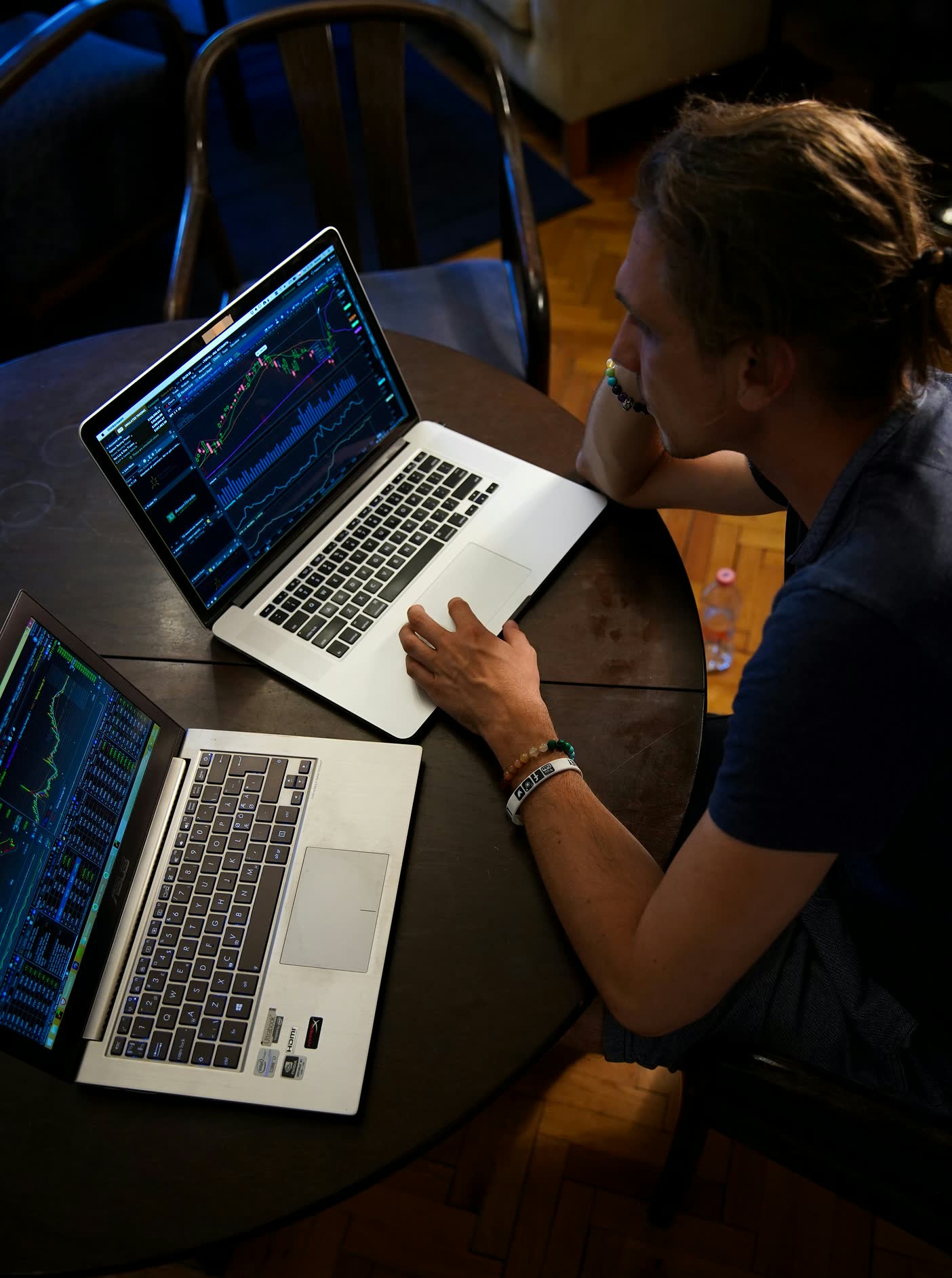 A trader watching market charts on two laptops side by side